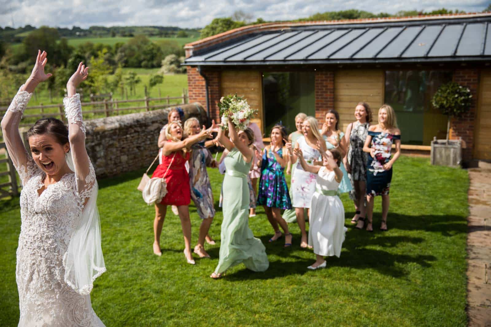 A bride with her bridesmaids waving their arms in the air captured by a Dodford Manor Wedding Photographer.