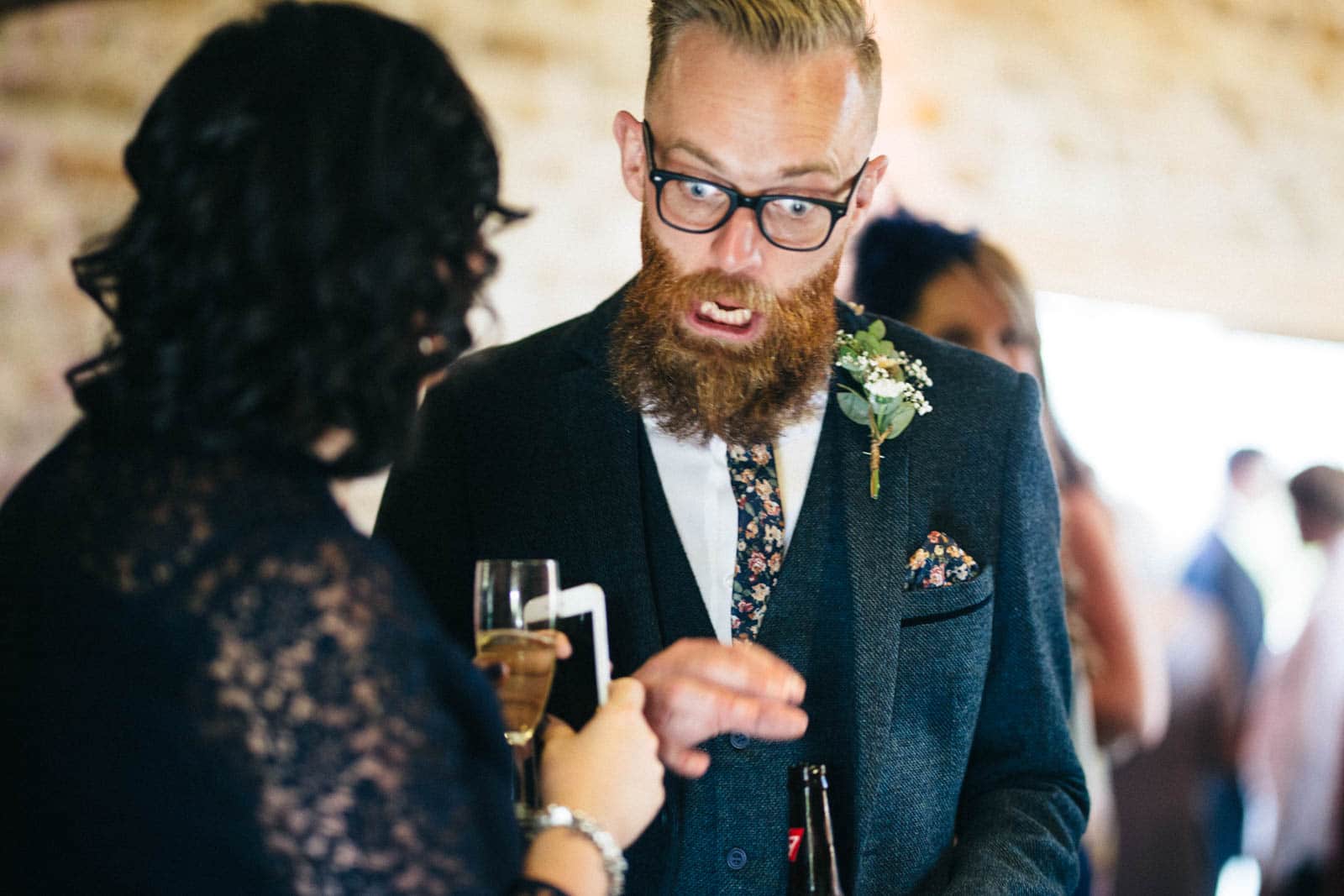A Dodford Manor Wedding Photographer capturing moments of a bearded man engaged in conversation with another man.
