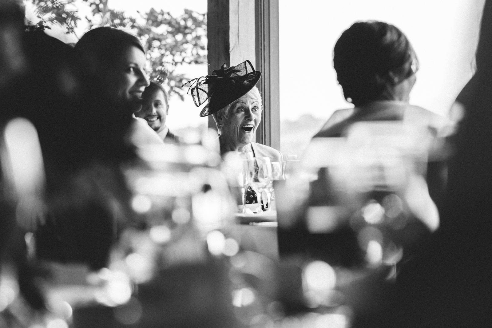A black and white photo of a woman sitting at a table captured by Dodford Manor Wedding Photographer.