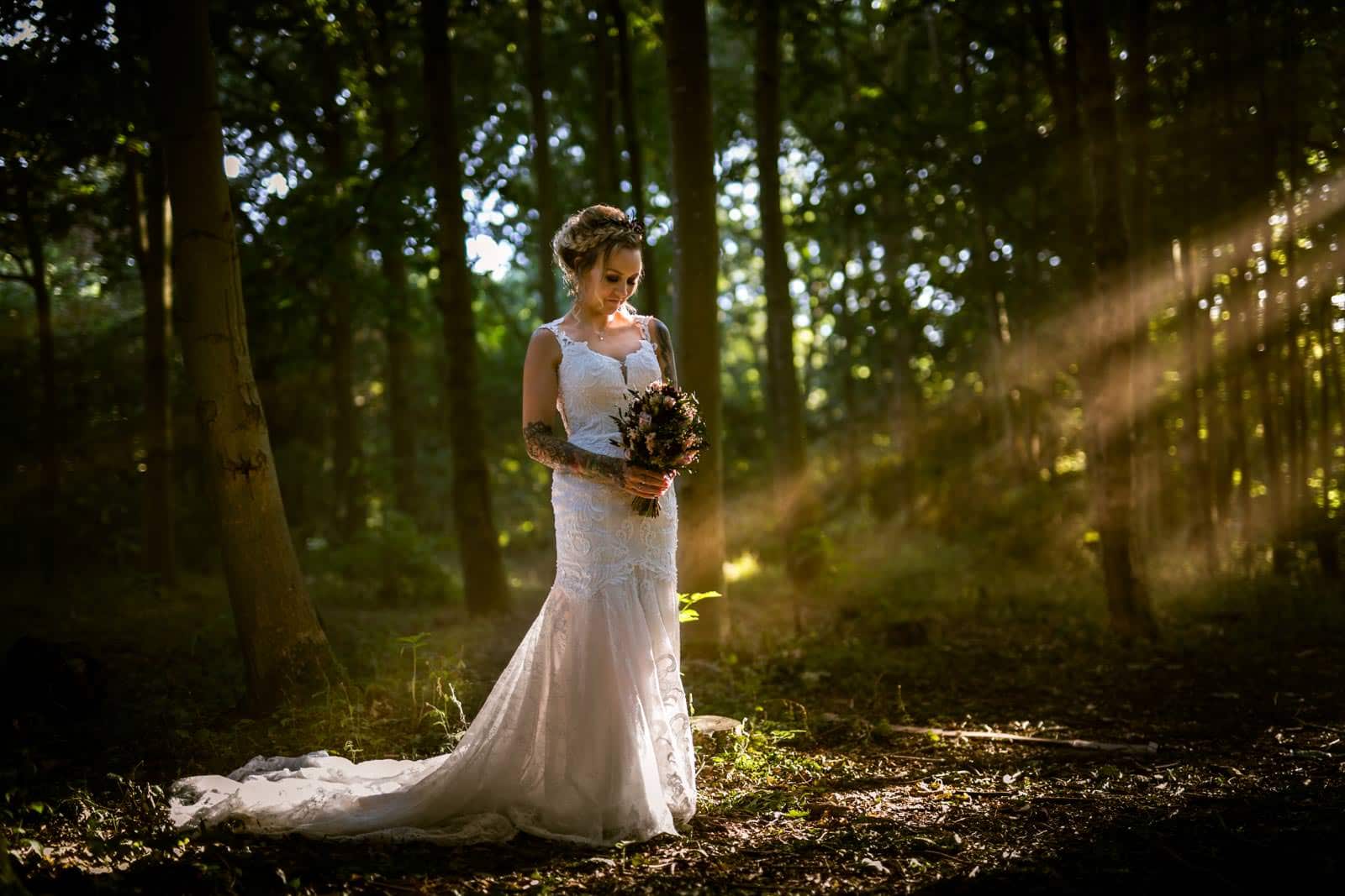 Beautiful photo taken at hunsbury hill center in Northampton. Bride standing in the forest being lit by sun beams