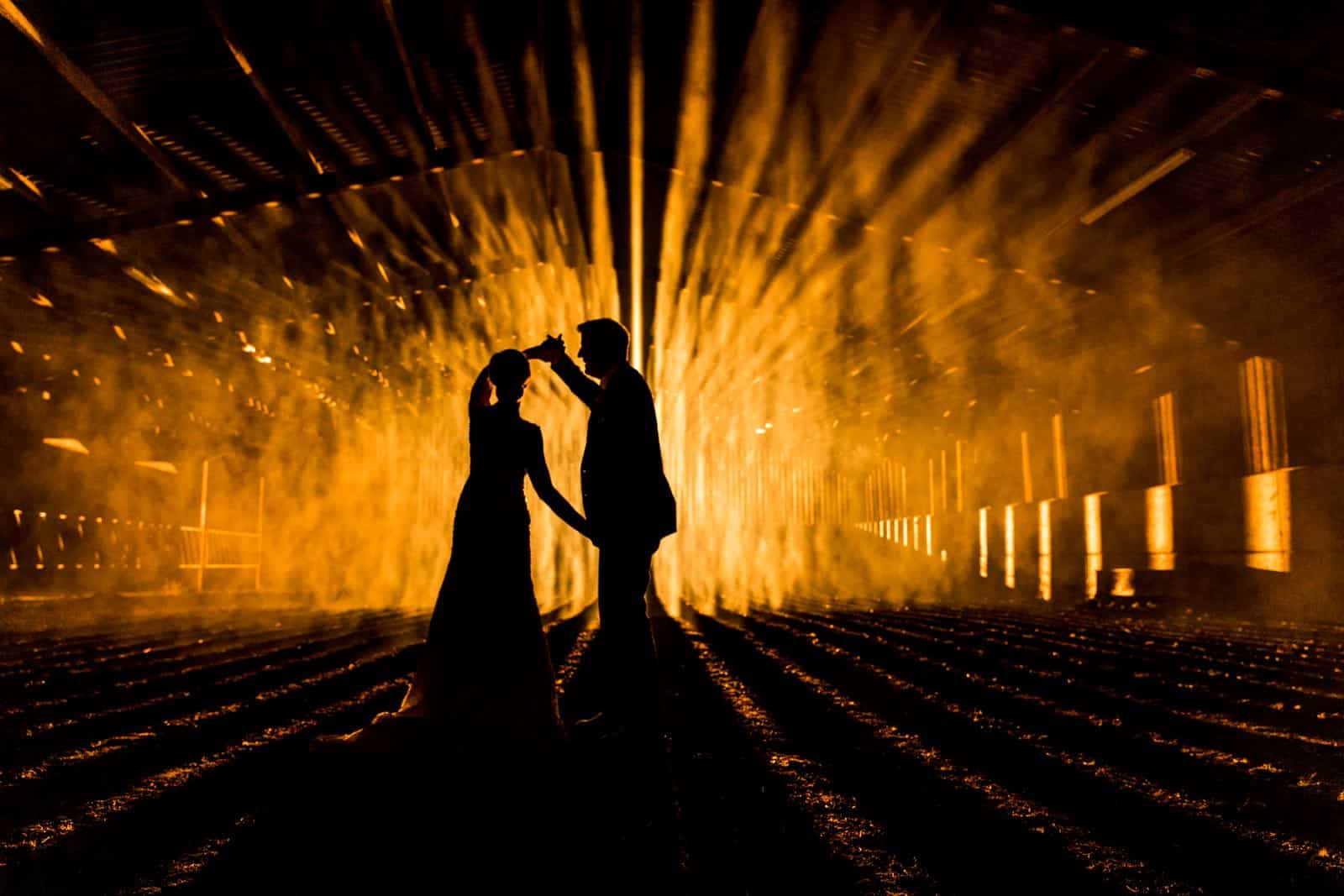 Stunning wedding silhouette photo of a couple in a barn at night, photo taken at Wood Farm Everdon